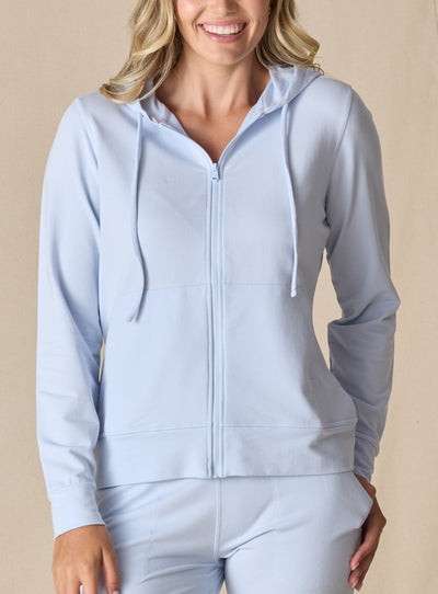 Women's Mesa Hooded Jacket in Powder, front model view featuring a soft blue full-zip hoodie with drawstring hood, center zip closure, and long sleeves paired with matching pants