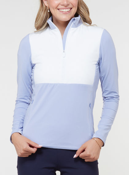 Women's Althea Half Zip in Lavender, front view on model featuring a color-blocked white quilted front panel with soft lavender blue knit sleeves and lower body, half-zip stand collar, and zippered side pockets, paired with navy pants