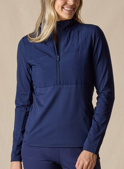 Women's Althea Half Zip in New Indigo, front view on model featuring a tonal navy lightly quilted front panel with navy knit sleeves and lower body, half-zip stand collar, and zippered side pockets, paired with matching navy pants