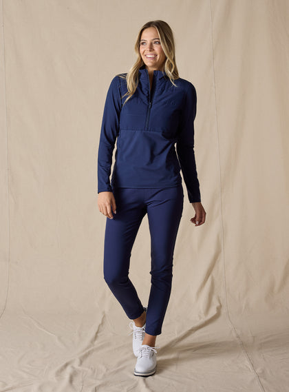 Women's Althea Half Zip in New Indigo, full-length front view on model featuring a tonal navy lightly quilted front panel with navy knit sleeves and lower body, paired with matching navy pants and white shoes