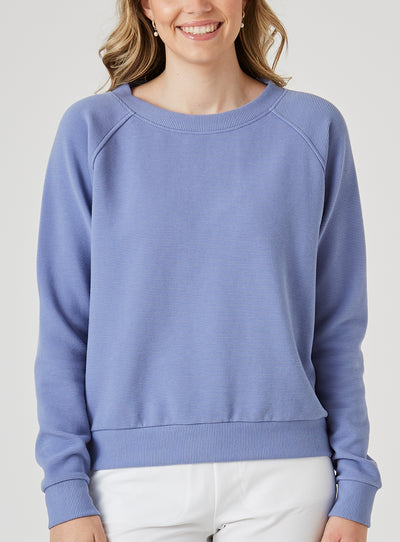 Delia Sweatshirt in Blueberry, front view on model featuring a medium blue ribbed-texture crewneck pullover with raglan sleeves and ribbed hem styled with white pants