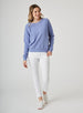 Delia Sweatshirt in Blueberry, full length front view on model featuring a medium blue ribbed-texture crewneck pullover with raglan sleeves and ribbed hem styled with white pants and white shoes