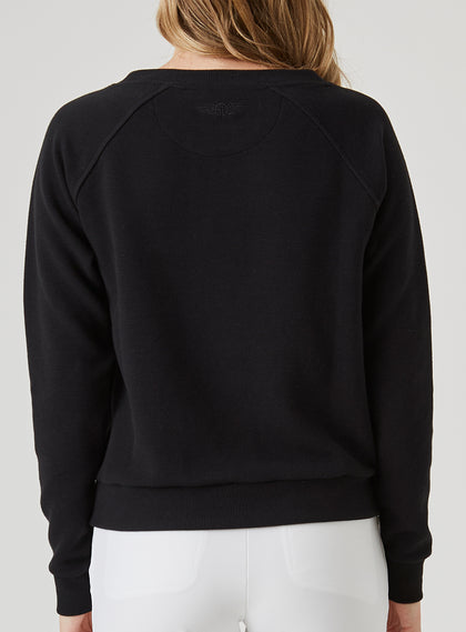 Delia Sweatshirt in Black, back view on model featuring a black ribbed-texture crewneck pullover with raglan sleeves and tonal embroidered logo detail at the center back neck styled with white pants