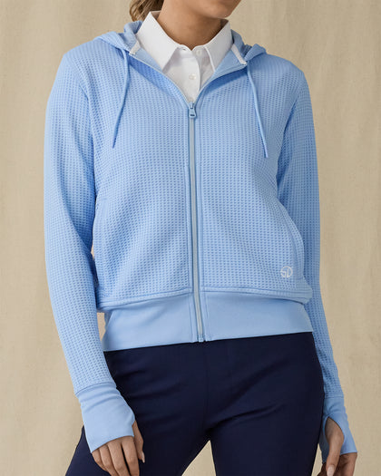 Eliza Hoodie in Carolina, front view on model showing a light blue waffle-knit full zip hoodie with drawstring hood, layered over a white polo, paired with navy pants