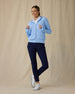 Eliza Hoodie in Carolina, full length front view on model showing a light blue waffle-knit full zip hoodie with drawstring hood, layered over a white polo, paired with navy pants and white golf shoes