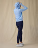 Eliza Hoodie in Carolina, full length back view on model showing a light blue waffle-knit full zip hoodie with hood up, paired with navy pants and white golf shoes