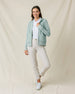Full-length view of a model wearing the Eliza Hoodie in Herb with a white polo, light-colored pants, and golf shoes.