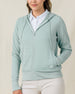 Front view of a model wearing the Eliza Hoodie in Herb partially zipped, highlighting the textured waffle knit, drawcord hood, and front pockets.