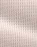 A close-up of a textured fabric with a repeating waffle or bubble pattern in a very light blush pink color.