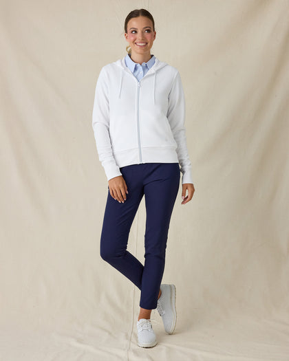 Eliza Hoodie in White, full length front view on model showing a white waffle-knit full zip hoodie with drawstring hood, layered over a light blue polo, paired with navy pants and white golf shoes