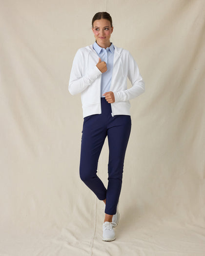 Eliza Hoodie in White, full length front view on model showing a white waffle-knit full zip hoodie open at the front, layered over a light blue polo, paired with navy pants and white golf shoes