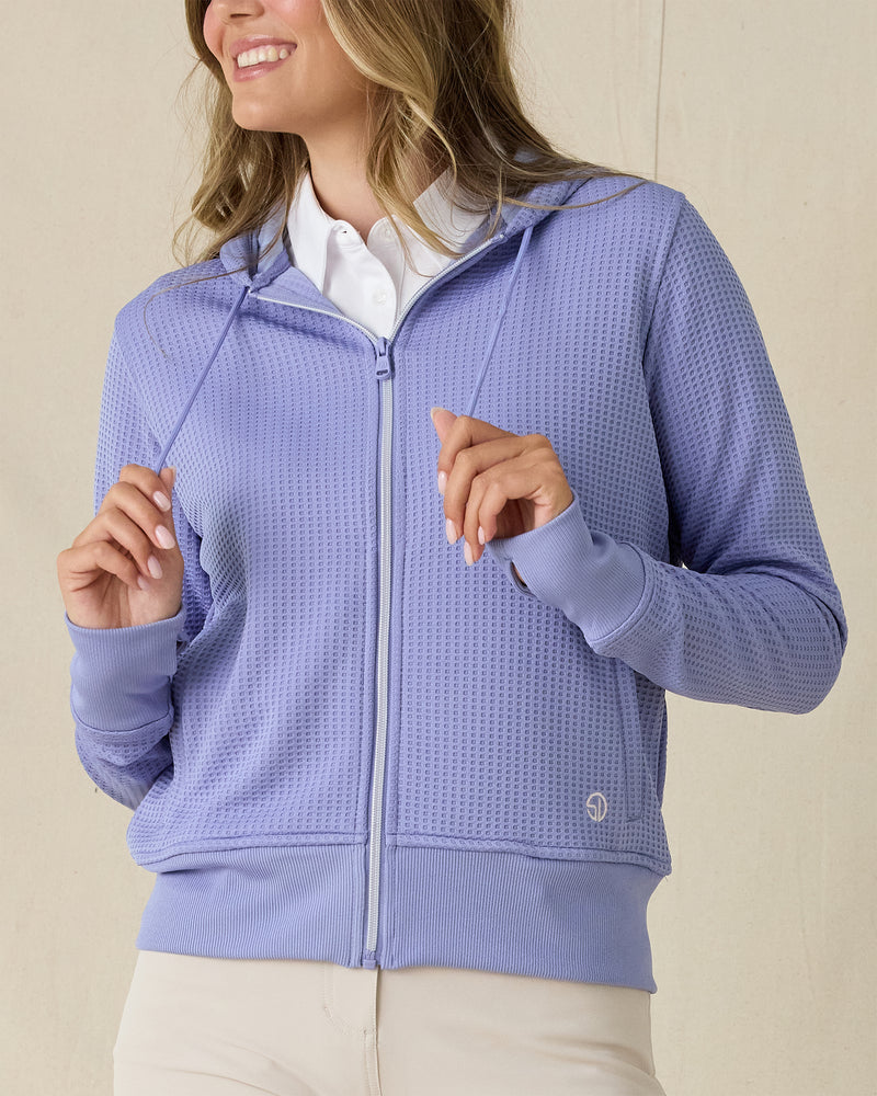 Eliza Hoodie in Blue Shade, front view on model in solid blue waffle knit texture with full zip and drawstring hood, layered over a white polo