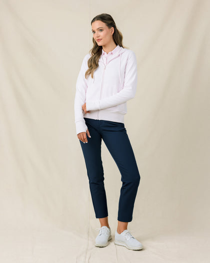 Woman wearing the Straight Down Eliza Hoodie in Pale Pink zipped up with navy golf pants
