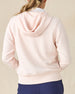 Eliza Hoodie in Pearl, back view featuring a blush pink waffle knit full zip hoodie, layered over a white polo and paired with navy pants