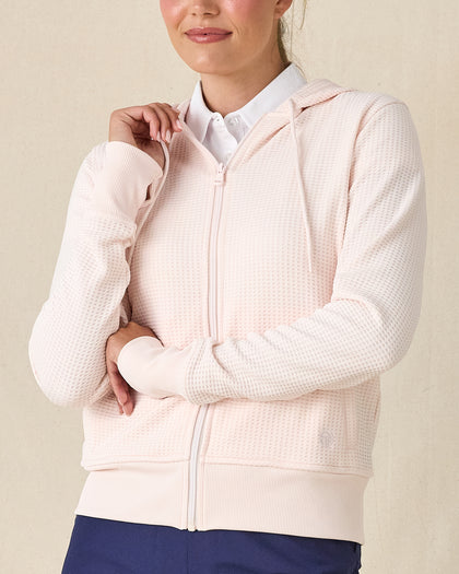 Eliza Hoodie in Pearl, front view featuring a blush pink waffle knit full zip hoodie with drawstring detail, layered over a white polo and paired with navy pants