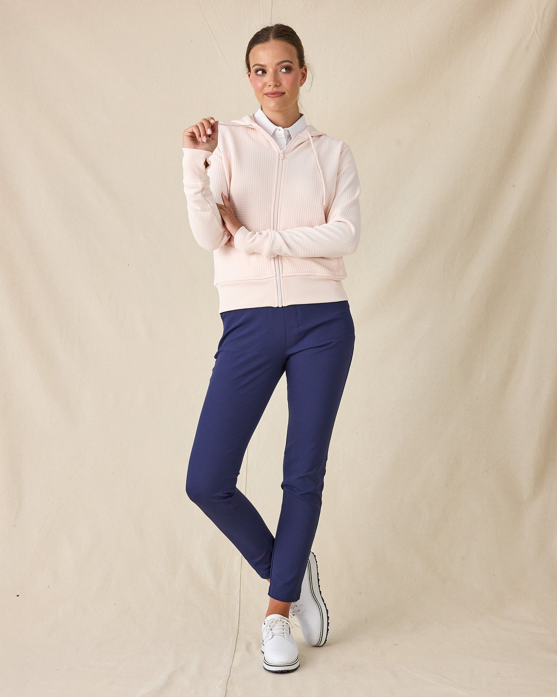 Eliza Hoodie in Pearl, full length front view featuring a blush pink waffle knit full zip hoodie, layered over a white polo and paired with navy ankle pants and white golf shoes