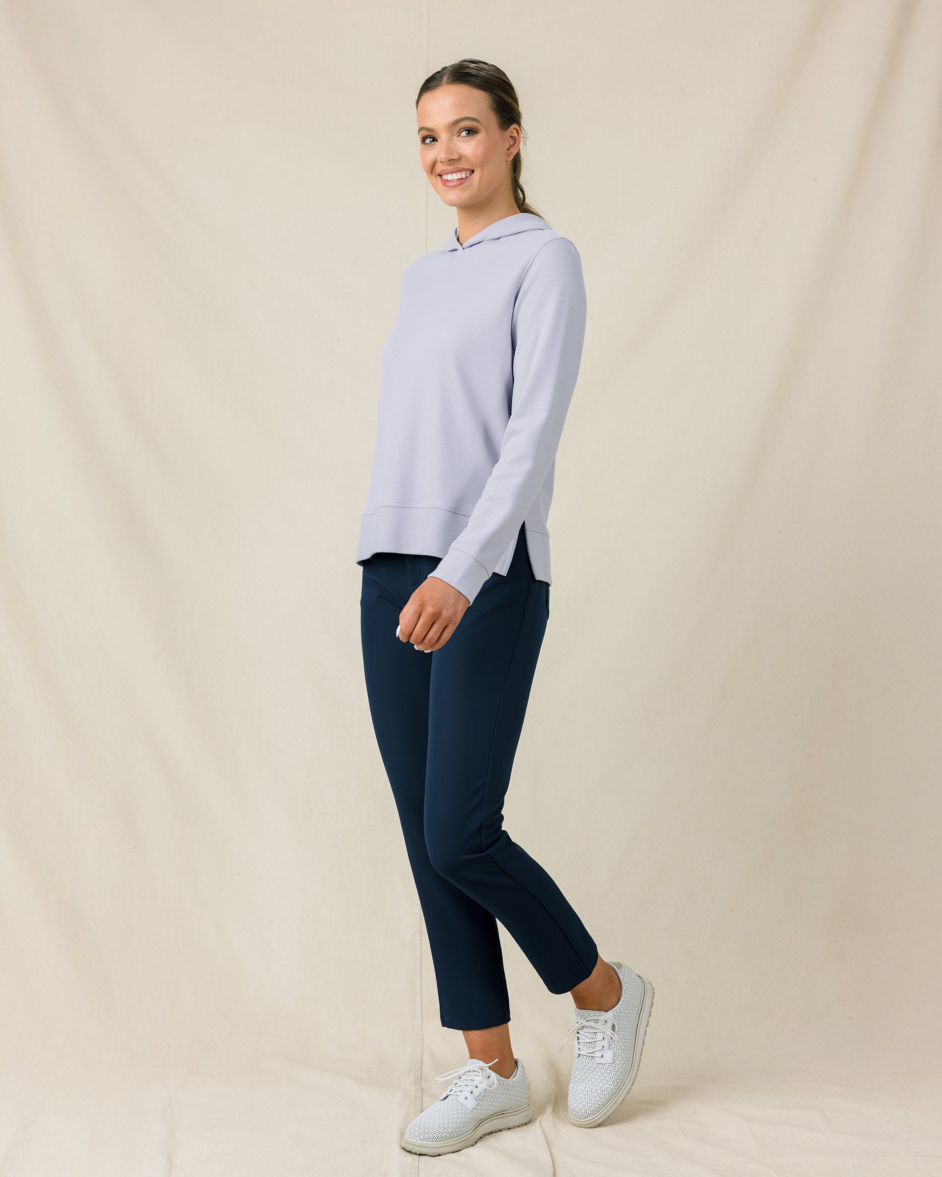 Woman wearing the Straight Down Daria Hoodie in Cosmic Blue with navy golf pants, side view