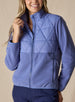 Women's Laurel Hybrid Fleece Jacket in Blueberry, front view on model featuring a medium blue quilted upper body with fleece lower body and sleeves, full-zip closure, and side zip pocket paired with navy pants