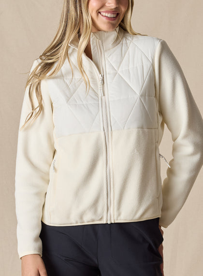 Women's Laurel Hybrid Fleece Jacket in Cream, front view on model featuring a cream quilted upper body with fleece lower body and sleeves, full-zip closure, and side zip pockets paired with black pants