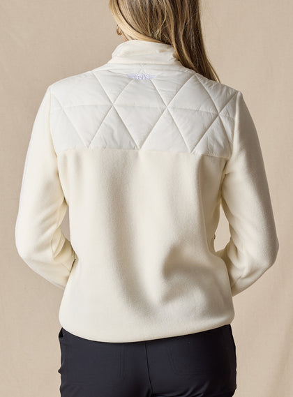 Women's Laurel Hybrid Fleece Jacket in Cream, back view on model featuring a cream quilted upper body with fleece lower body and sleeves, full-zip closure, and side zip pockets paired with black pants