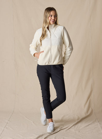 Women's Laurel Hybrid Fleece Jacket in Cream, full body front view on model featuring a cream quilted upper body with fleece lower body and sleeves, full-zip closure, and side zip pockets paired with black pants
