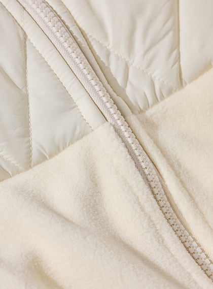 Women's Laurel Hybrid Fleece Jacket in Cream, close-up detail view featuring the full-zip closure showing the contrast between the quilted upper panel and soft fleece lower body
