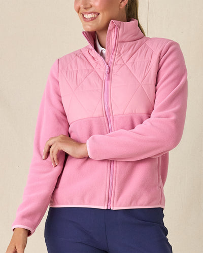 Women's Laurel Hybrid Fleece Jacket in Sweet Rose, front view on model featuring a pink hybrid jacket with diamond quilted upper body panel and fleece sleeves, layered over a white polo, paired with navy pants