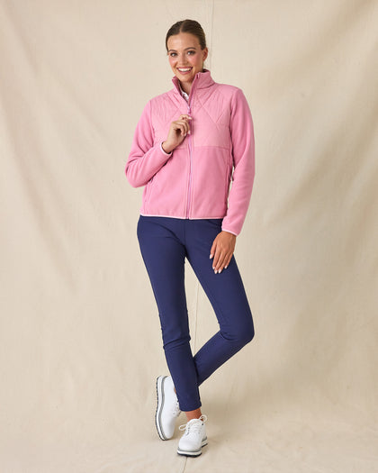Women's Laurel Hybrid Fleece Jacket in Sweet Rose, full length front view on model featuring a pink hybrid jacket with diamond quilted upper body panel and fleece sleeves, layered over a white polo, paired with navy pants and white golf shoes