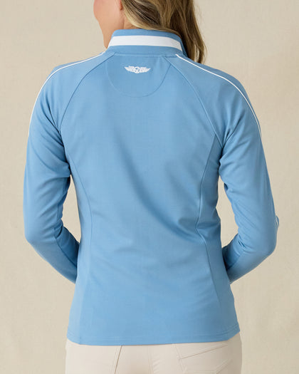 Patty Jacket in Coastal, back view on model featuring a solid medium blue full zip jacket with white piping along the sleeves and Straight Down embroidered logo at the upper back, paired with khaki pants
