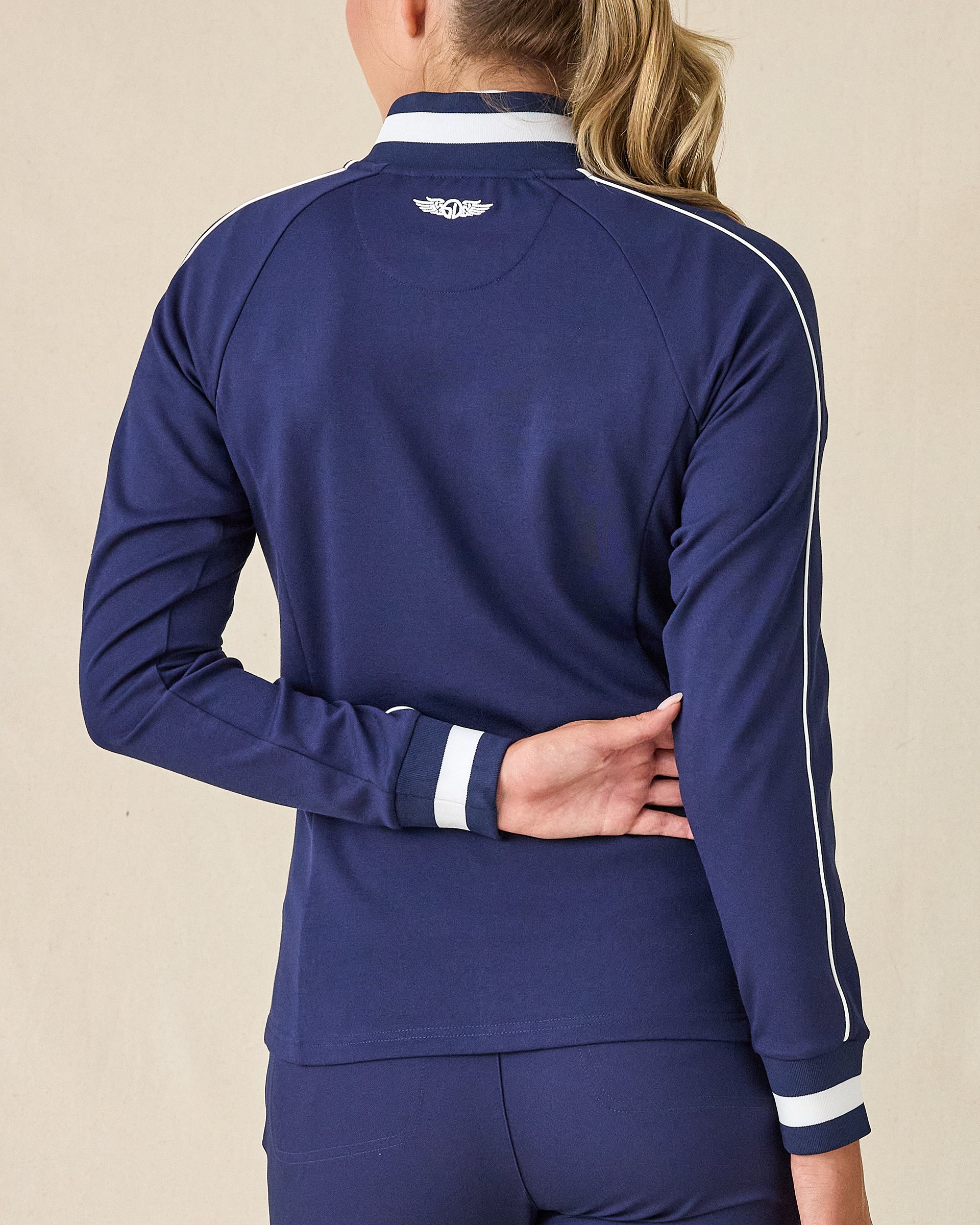 Patty Jacket in New Indigo, back view on model in solid navy with white contrast piping along the sleeves and Straight Down logo embroidered at center back
