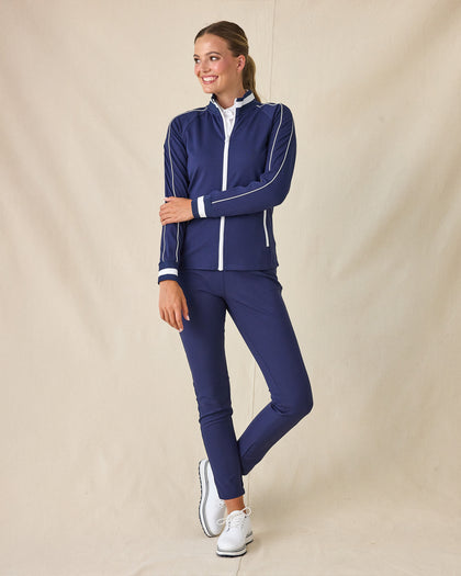 Patty Jacket in New Indigo, full-length front view on model in solid navy with white contrast piping, paired with navy pants and white golf shoes