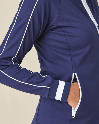 Patty Jacket in New Indigo, close-up detail view on model featuring white contrast piping along the sleeve, white striped cuff, and zip pocket