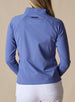 Women's Eirene Jacket in Blueberry, back view on model featuring a solid cornflower blue performance fabric with raglan sleeve construction and tonal Straight Down logo at the upper back, paired with white pants