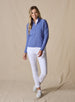 Women's Eirene Jacket in Blueberry, full-length front view on model featuring a solid cornflower blue performance fabric with a full-zip stand collar and raglan sleeves, layered over a white polo and paired with white pants and white shoes