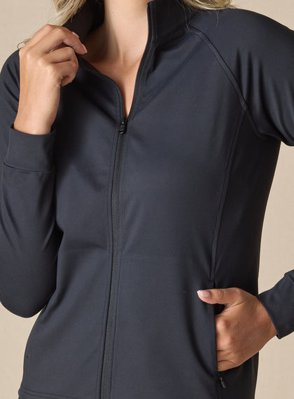 Women's Eirene Jacket in Black, close-up detail view featuring the full-zip stand collar and raglan sleeve construction with model's hand in the zippered side pocket, showcasing the solid black performance fabric