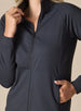 Women's Eirene Jacket in Black, close-up detail view featuring the full-zip stand collar and raglan sleeve construction with model's hand in the zippered side pocket, showcasing the solid black performance fabric
