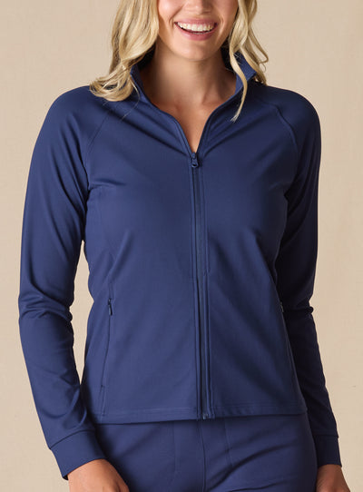 Women's Eirene Jacket in New Indigo, front view on model featuring a solid navy performance fabric with a full-zip stand collar and raglan sleeves, with zippered side pocket detail, paired with matching navy pants