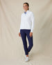 Women's Eirene Jacket in White, full-length front view on model featuring a clean white performance fabric with a full-zip stand collar and raglan sleeves, layered over a light blue polo and paired with navy pants and white shoes