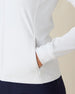 Women's Eirene Jacket in White, close-up detail view featuring a zippered side pocket with model's hand inserted, showcasing the clean white performance fabric and ribbed cuff