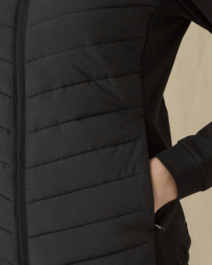 Women's 126th U.S. Open Ida Hybrid Jacket in Black, close-up model view featuring the horizontal quilted texture and side zip pocket detail