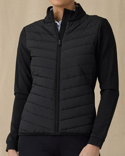 Women's Ida Hybrid Jacket in Black, front view on model featuring a black full zip jacket with a quilted front body panel and smooth stretch sleeves, paired with black pants