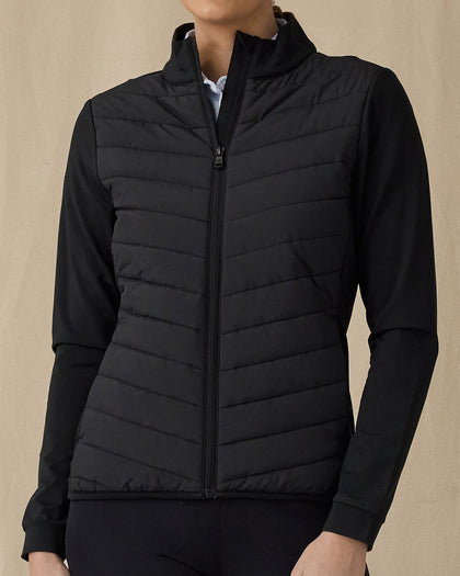 Women's Ida Hybrid Jacket in Black, front view on model featuring a black full zip jacket with a quilted front body panel and smooth stretch sleeves, paired with black pants