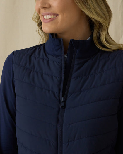 Women's Ida Hybrid Jacket in New Indigo, front close-up view featuring horizontal quilted stitching detail, full-zip closure with stand collar, and stretch side panels