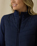 Women's Ida Hybrid Jacket in New Indigo, front close-up view featuring horizontal quilted stitching detail, full-zip closure with stand collar, and stretch side panels