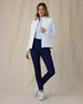 Women's Ida Hybrid Jacket in White, front full-length view featuring an open zip, horizontal quilted front body, and stretch side panels paired with navy pants and white shoes worn over a light blue polo