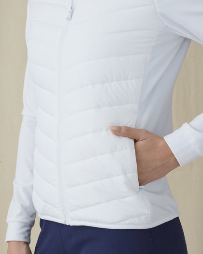 Women's Ida Hybrid Jacket in White, side close-up view featuring a hand inserted into the side pocket, horizontal quilted stitching detail, and stretch side panel