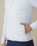 Women's Ida Hybrid Jacket in White, side close-up view featuring a hand inserted into the side pocket, horizontal quilted stitching detail, and stretch side panel