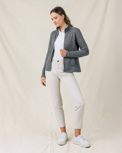 Full-length view of a model wearing the Marlow Jacket in Nightshade open over a white polo with light-colored pants and golf shoes.