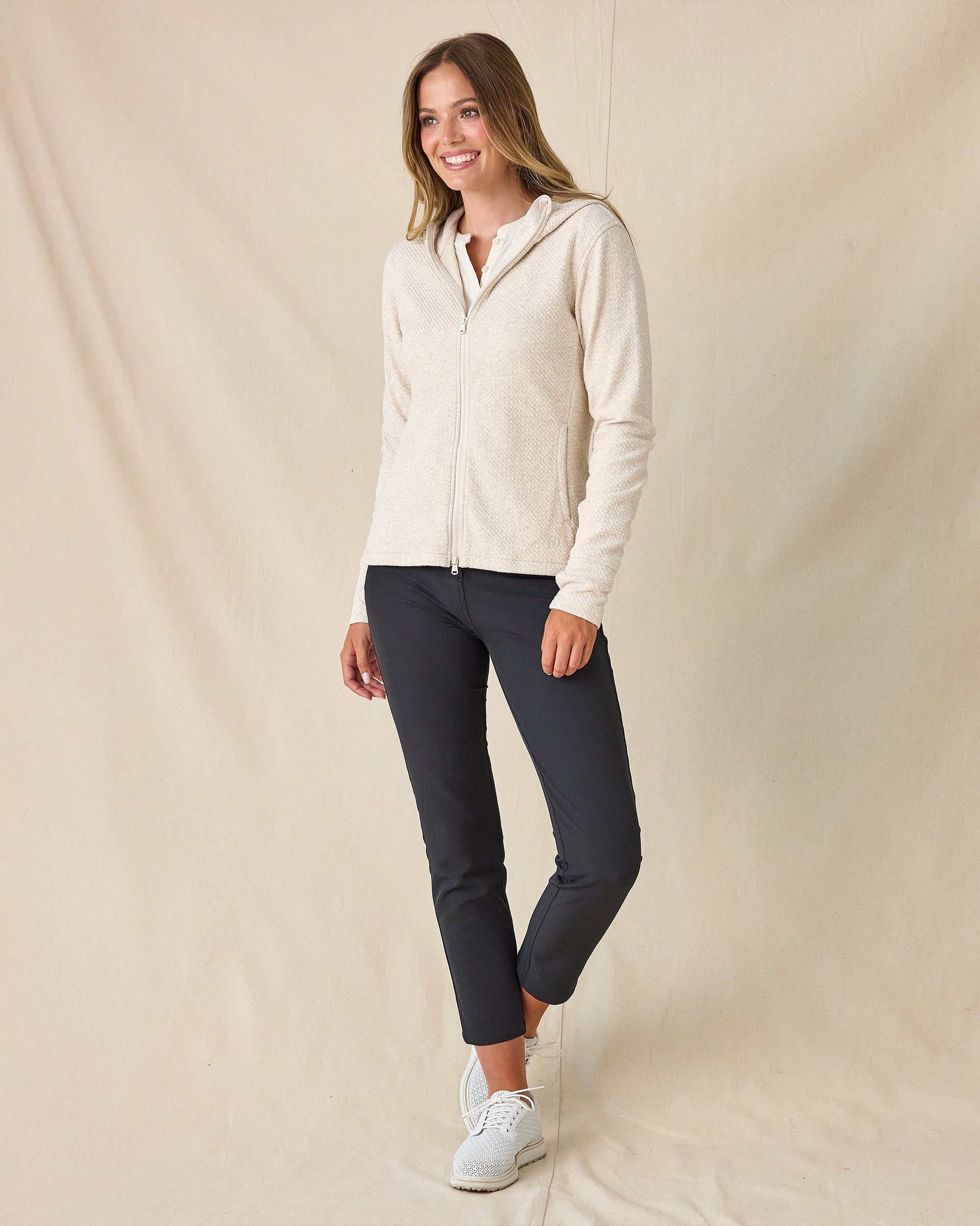 Highland Hooded Jacket in Oatmeal Heather, full length front view on model featuring an oatmeal heather textured fleece full zip hooded jacket, layered over a white polo and paired with charcoal ankle pants and white golf shoes