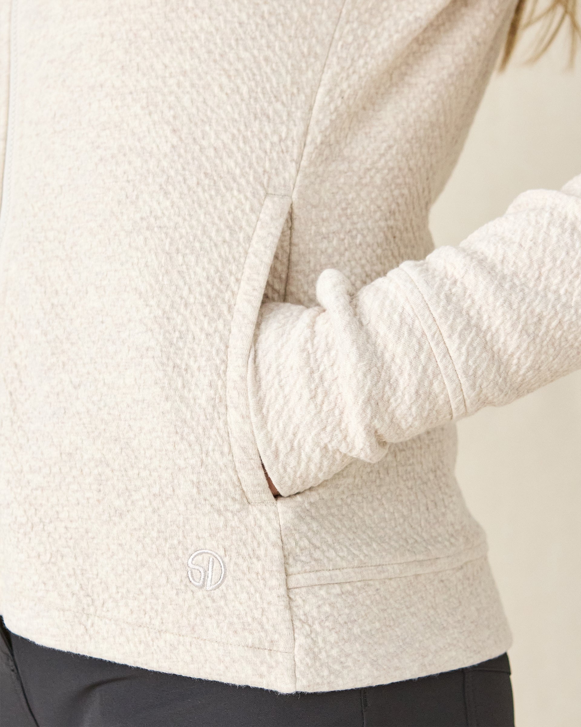 Highland Hooded Jacket in Oatmeal Heather, close-up detail view on model featuring the textured fleece fabric, side pocket, and Straight Down embroidered logo